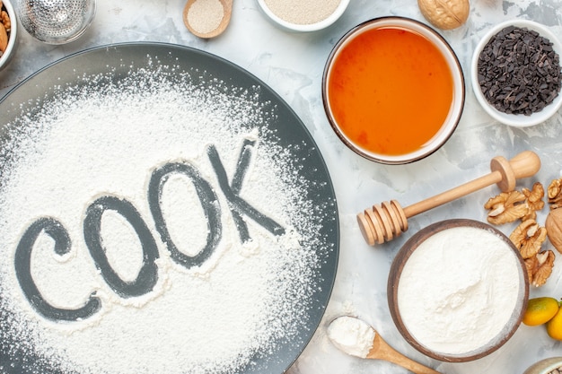 top view cook written flour with cereals eggs seeds nuts and jelly on the white surface