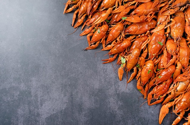 Top view of cooked crawfish with lemons and spices on dark cement background