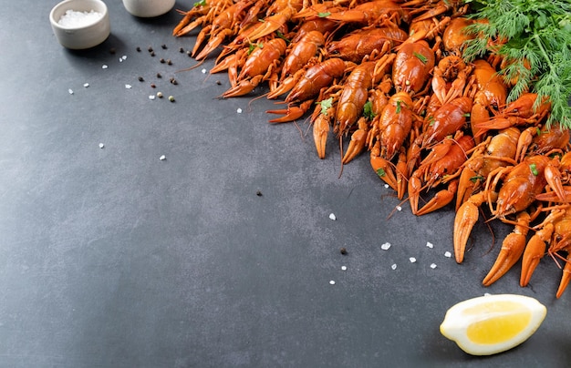 Top view of cooked crawfish with lemons and spices on dark cement background