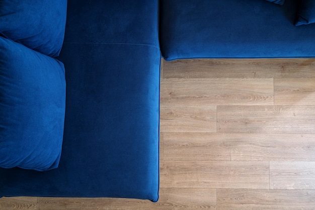 Top view of corner couch with blue upholstery and cushions on laminate floor