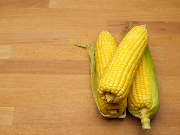 Top view of corns and corn on the cop isolated on wooden table with copy space