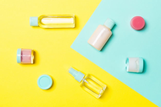 Top view of cosmetic containers, sprays, jars and bottles on yellow and blue . Close-up view 