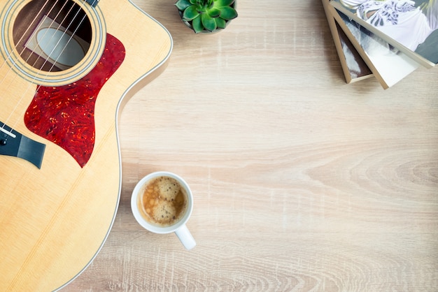 Top view of cosy home scene. Guitar, books, cup of coffee, phone and succulent plants over wood. Copy space, mock-up.