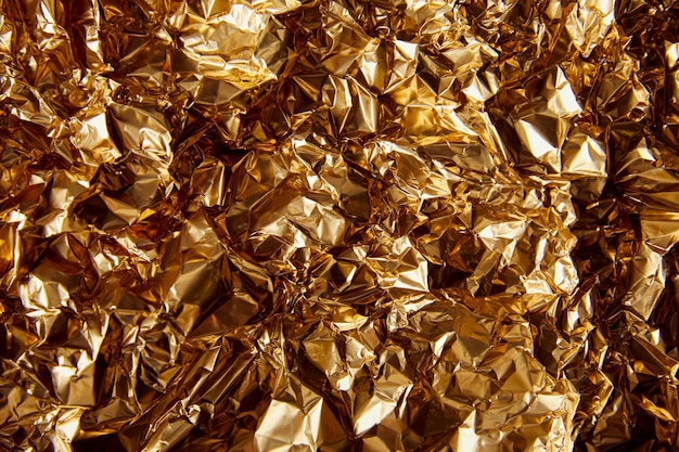 Top view of crumpled golden foil with glares