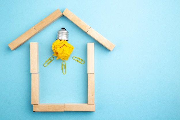 top view crumpled paper with idea light bulb concept in house shaped wood blocks on blue background free space