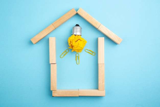 top view crumpled paper with idea light bulb concept in house shaped wood blocks on blue background