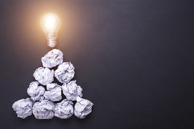 Top view crumpled white paper and light bulbs on black stone board