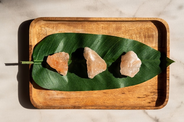 Top view of crystals of pink himalayan salt on green leaf surface