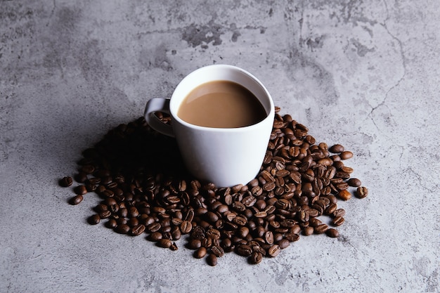 Top view A cup of cappuccino coffee surrounded by coffee beans in the middle of a texture table