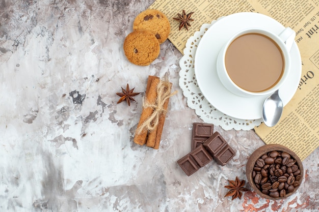 top view cup of coffee bowl with roasted coffee beans chocolate cinnamon sticks biscuits on table with copy place