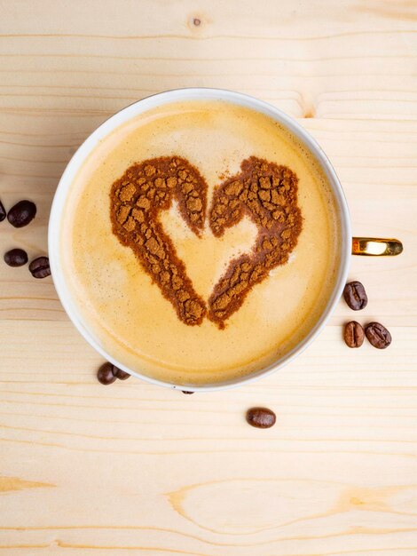 Top view of cup of coffee with heart drawing coffee romantic art Valentine's Day A cup of cappuccino with barista heart shape pattern in a cup on wooden background