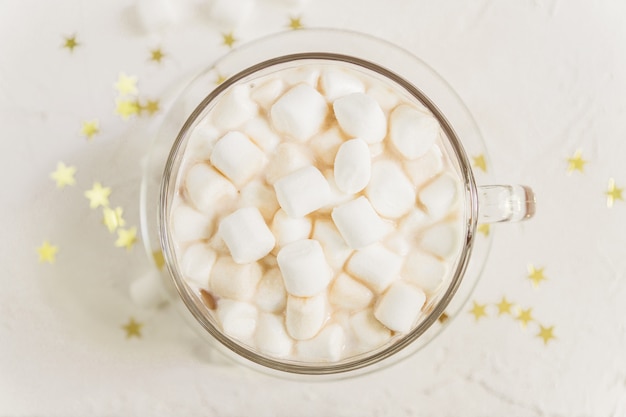 Top view of cup of hot delicious cocoa drink with marshmallows on gold stars