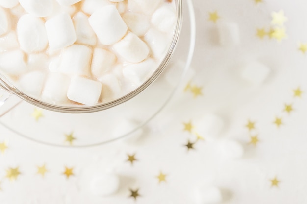 Top view of cup of hot delicious cocoa drink with marshmallows on gold stars