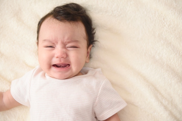 Top view of cute little Asian baby crying