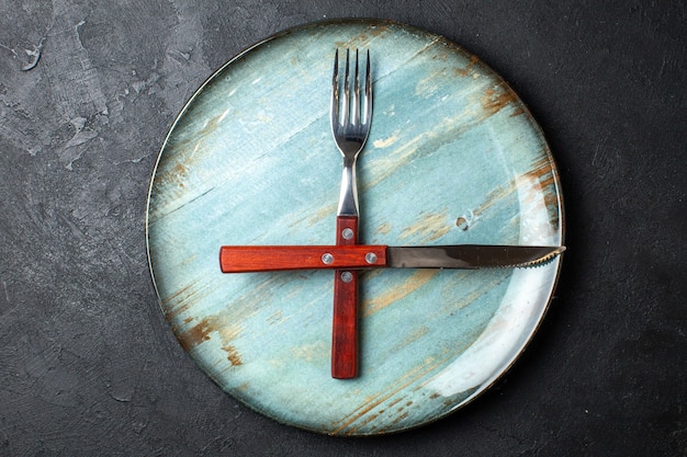 Top view of cutlery set on blue plate on balack background with free space