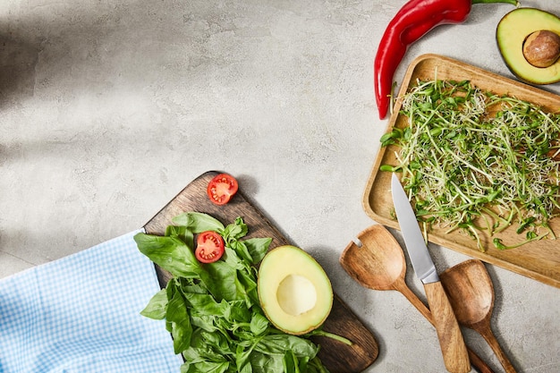 Top view of cutting boards with basil leaves microgreens cherry tomato and avocado halves with