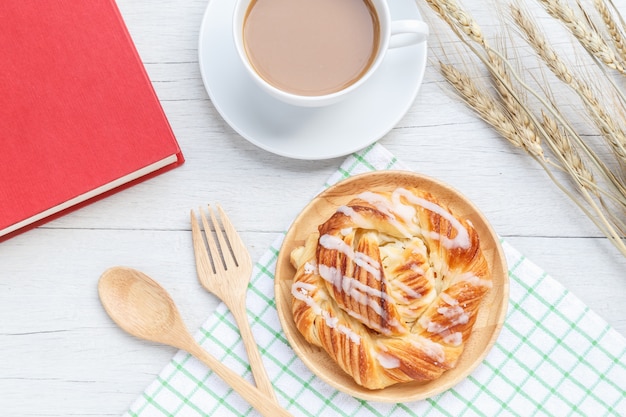 Top view danish pastries, coffee and note book on white wooden table