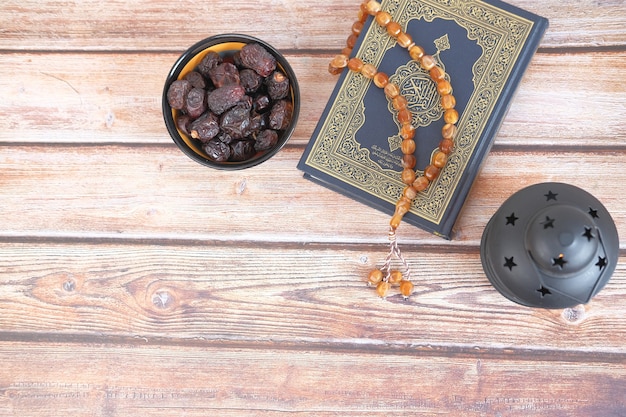 Top view of date fruit  holy book quran and rosary on table