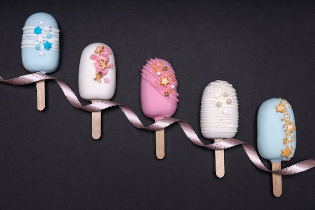 Top view of decorated cake pops ice creams on black background