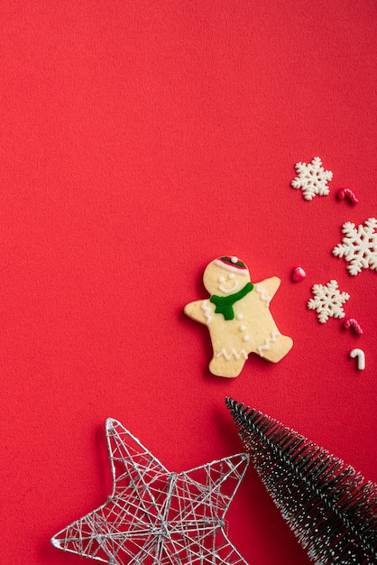 Top view of decorated Christmas gingerbread cookies with decorations on red table background with copy space, concept of holiday celebration.