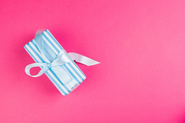 Top view of a decorated present with a bow on pink 