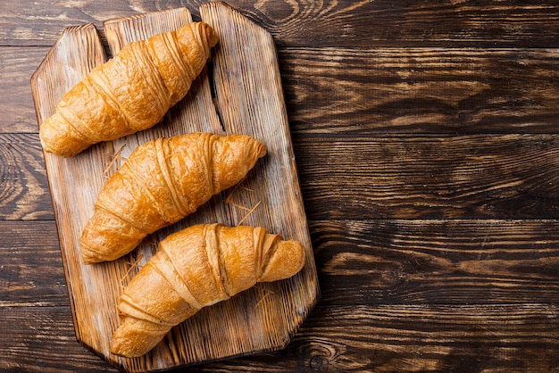 Top view delicious baked croissants on wooden board and copy space