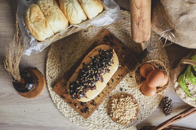 Top view of delicious bread with chocolate spread and sprinkled with nuts on top of it on a wooden b