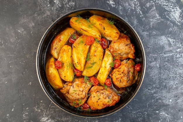 Top view of delicious dinner with chickens potatoes greens in saucepan on dark color background