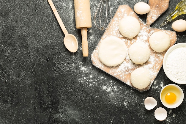 top view delicious dough with ingredients on a black background