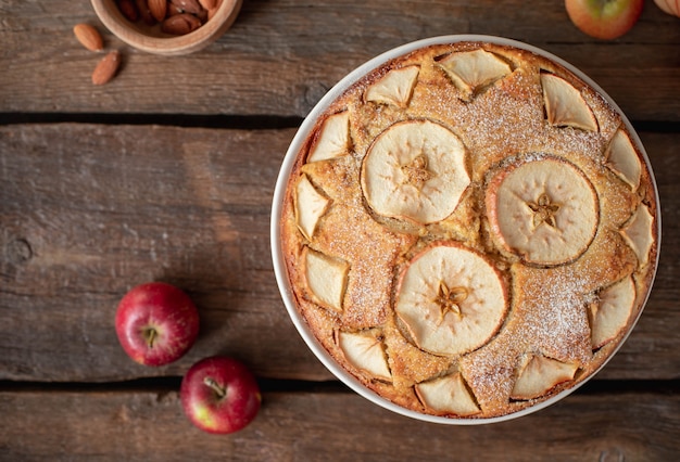 Top view of delicious fruit cake with apples and almonds on a dark wooden