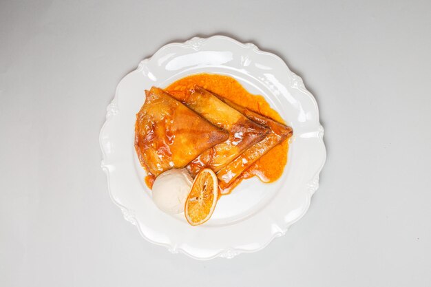 Top view of delicious pancakes with orange sauce and vanilla ice cream on a white background Maslenitsa