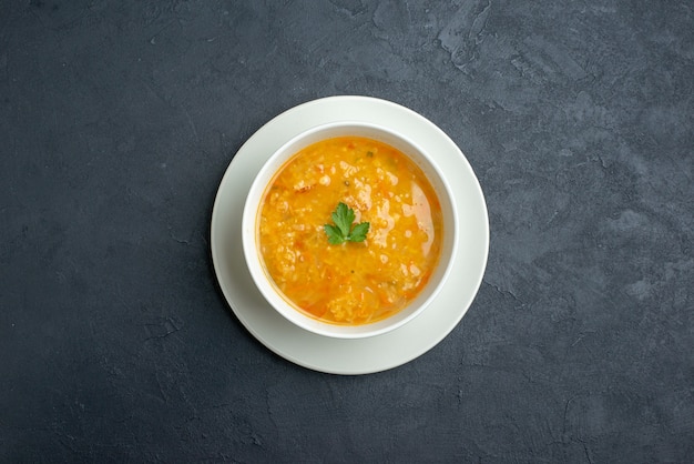 Top view delicious soup inside white plate on dark surface