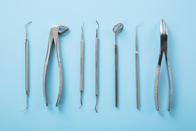 Top view of dental tools set on blue table in dentists clinic: dental mirror, explorers, forceps.