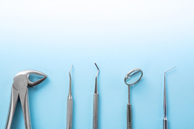 Top view of dental tools set on blue table in dentists clinic: dental mirror, explorers, forceps.