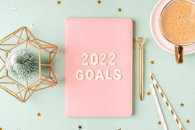 Top view desktop christmas pink notepad with goals letters text flat lay on green mint table