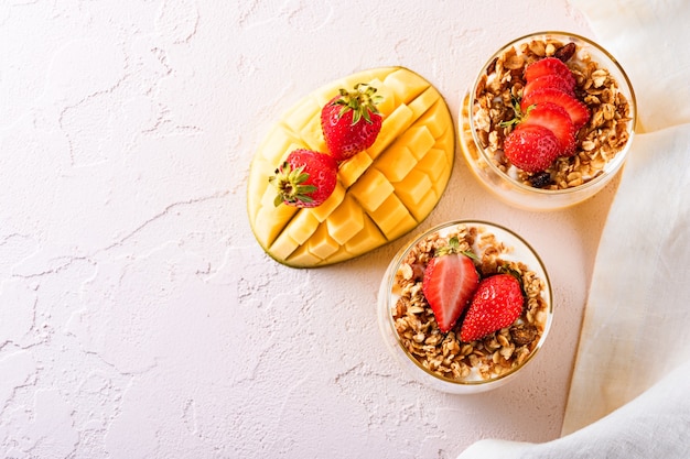 Top view dessert with mango and cheese mousse decorated with strawberry and granola with white napkin