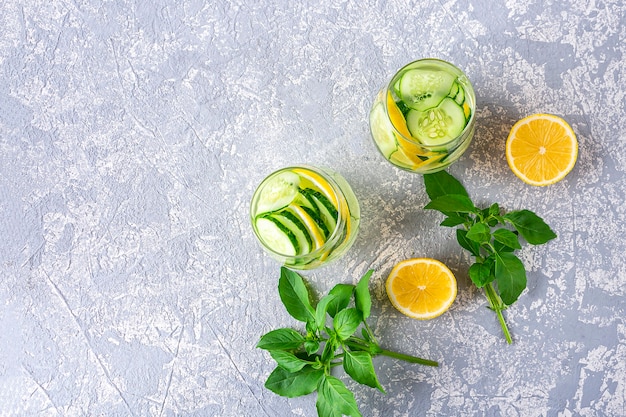 Photo top view detox water drink with cucumber and lemon on light grey textured background