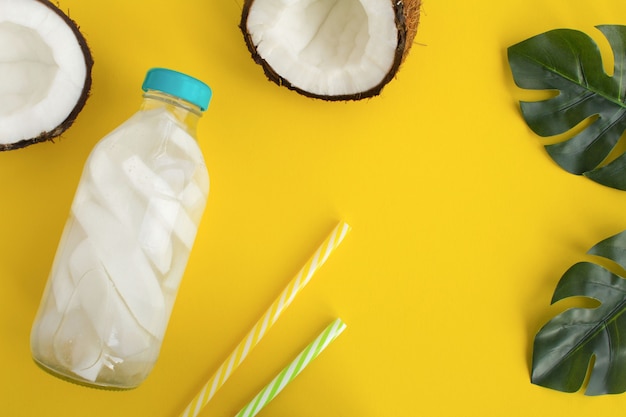 Top view of detox water with coconut in the glass bottle on the yellow