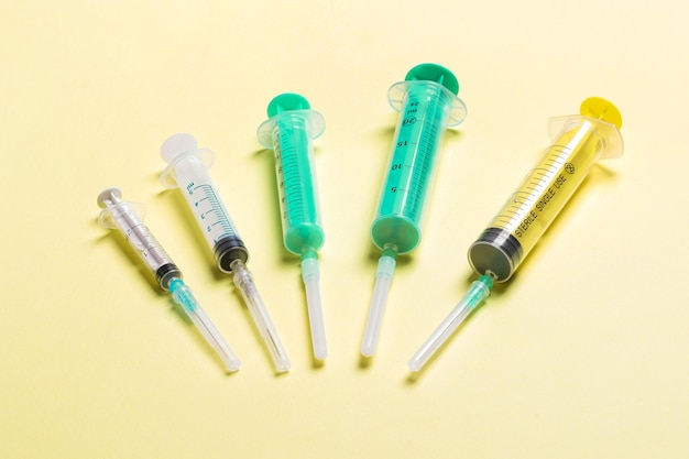 Top view of different syringes at yellow background Medical injection concept with copy space