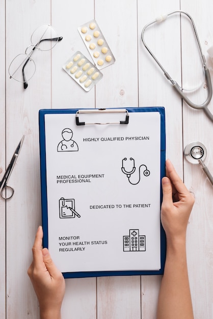 Top view of doctor desk with medical equipment at clinic/hospital. Stethoscope, prescription clipboard and bottle of pills on white surface with copy space. Health care and medical concept.