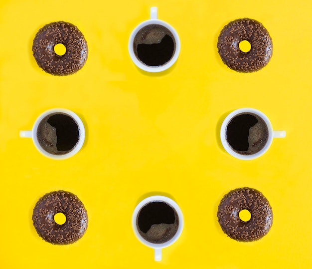 Top view of donut with chocolate glaze and coffee cup on the yellow background Flat lay Copy space