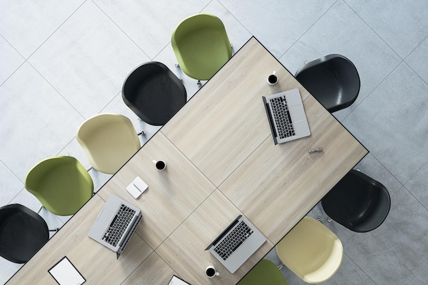 Top view of drawn wooden coworking office table with laptops, coffee cups, supplies and chairs