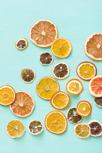 Top view on dried citrus chips orange lemon and grapefruit on turquoise background