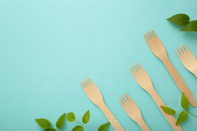 Photo top view of eco friendly cutlery, bamboo fork with leaves on blue background with copy space. top view