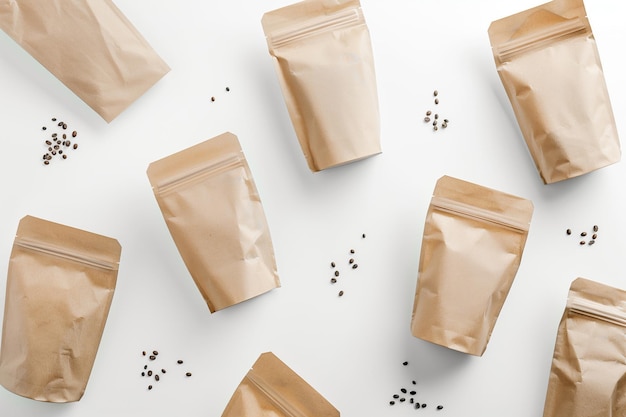 Top view of ecofriendly paper bags surrounded by scattered coffee beans ideal for branding mockups