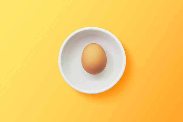 Top view of egg in bowl on orange background