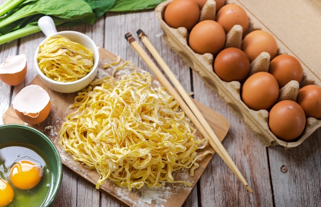 Top view of Egg Noodles ingredients like eggs, powder flour, egg yolk, cutting board, and chopstick