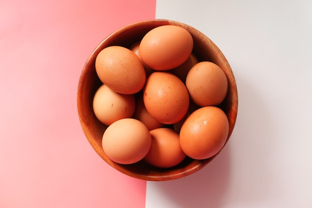 Top view of eggs in a bowl on color background