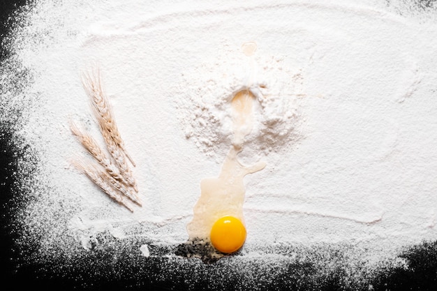 Top view eggs, dough, flour  on black table background