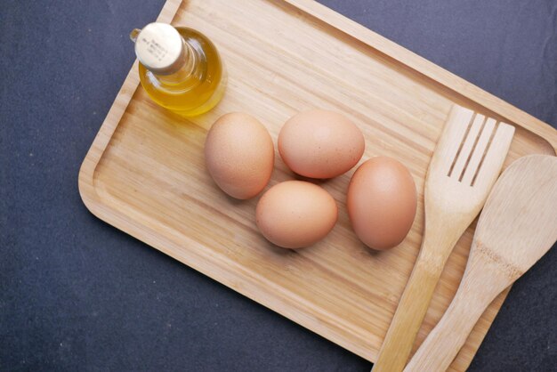 Top view of eggs oil and wooden spoon